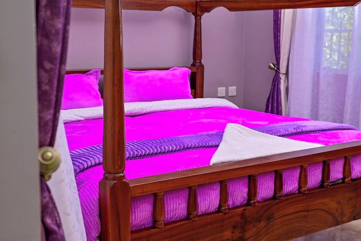 A four-poster bed with a wooden frame and a bright pink bedspread.