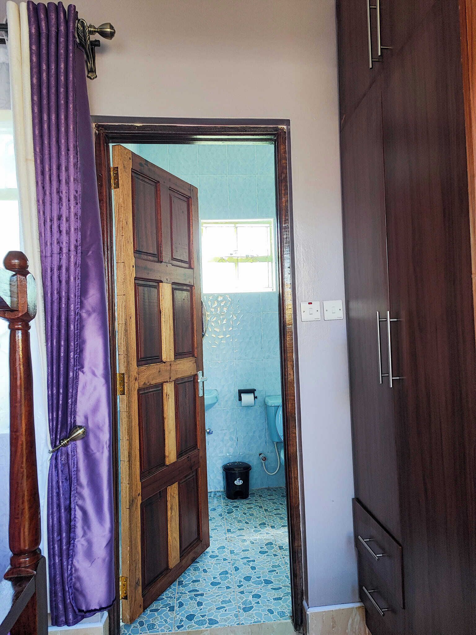 Een badkamer met een houten deur, een raam en een toilet.