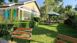Un'area esterna curata, con prato, panchine, un gazebo e un edificio caratterizzato da finestre dai colori vivaci.