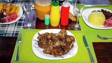 Uma mesa de jantar posta com pratos de comida, temperos e copos.