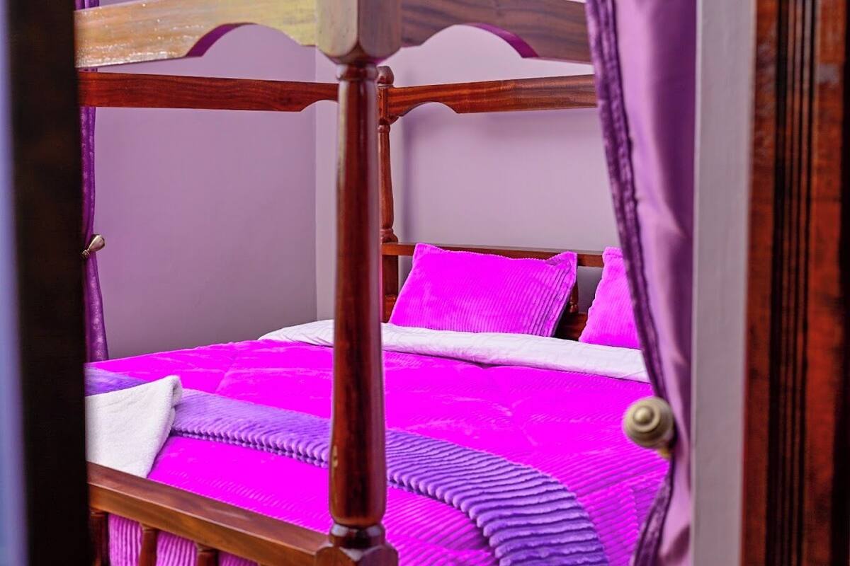 A bed with a wooden frame and a bright pink bedspread.