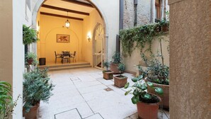 Un patio interior con zona de comedor, plantas en macetas y un muro de piedra.