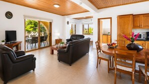 Een moderne woonkamer met een bank, televisie en een eetgedeelte met stoelen en een tafel.