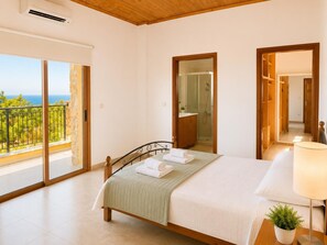 A bedroom with a bed, a bedside lamp, a potted plant, a bathroom with a shower, and a balcony with a view.
