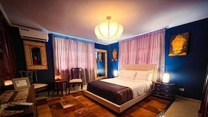 Un dormitorio con una cama grande, un escritorio con un ordenador portátil, una silla y una mesita con velas.