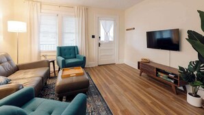 Ett modernt vardagsrum med en soffa, fåtöljer, ett soffbord, en tv och ett TV-bord i trä.