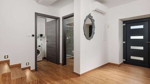 Interior moderno com escada de madeira, porta preta e espelho na parede.