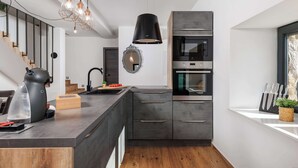 Cozinha moderna com ilha central, eletrodomésticos embutidos e luminária pendente.
