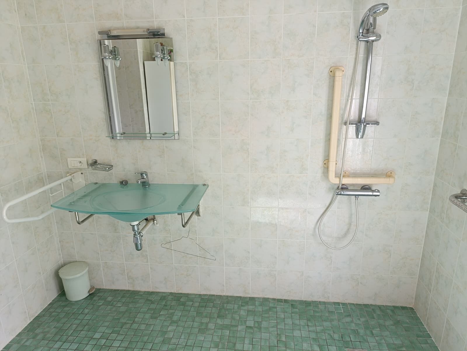 Une salle de bain avec un lavabo en verre, un miroir, une douche et des toilettes.