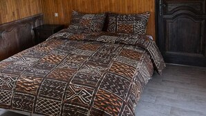 Ein Schlafzimmer mit schrägen Wänden, einer Holzwand, einer dunklen Tür und einer geblümten Bettdecke.