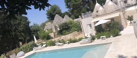 Una piscina al aire libre de temporada, sombrillas, tumbonas