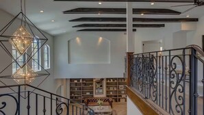 Ein großzügiger Innenraum mit Treppe, Bücherregalen und einer Hängeleuchte.