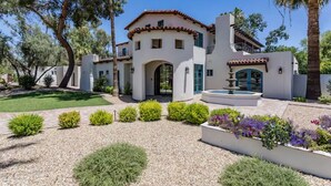 Eine mediterran gestaltete Villa mit Innenhof, Brunnen und gepflegtem Garten mit unterschiedlichen Pflanzen und Blumen.