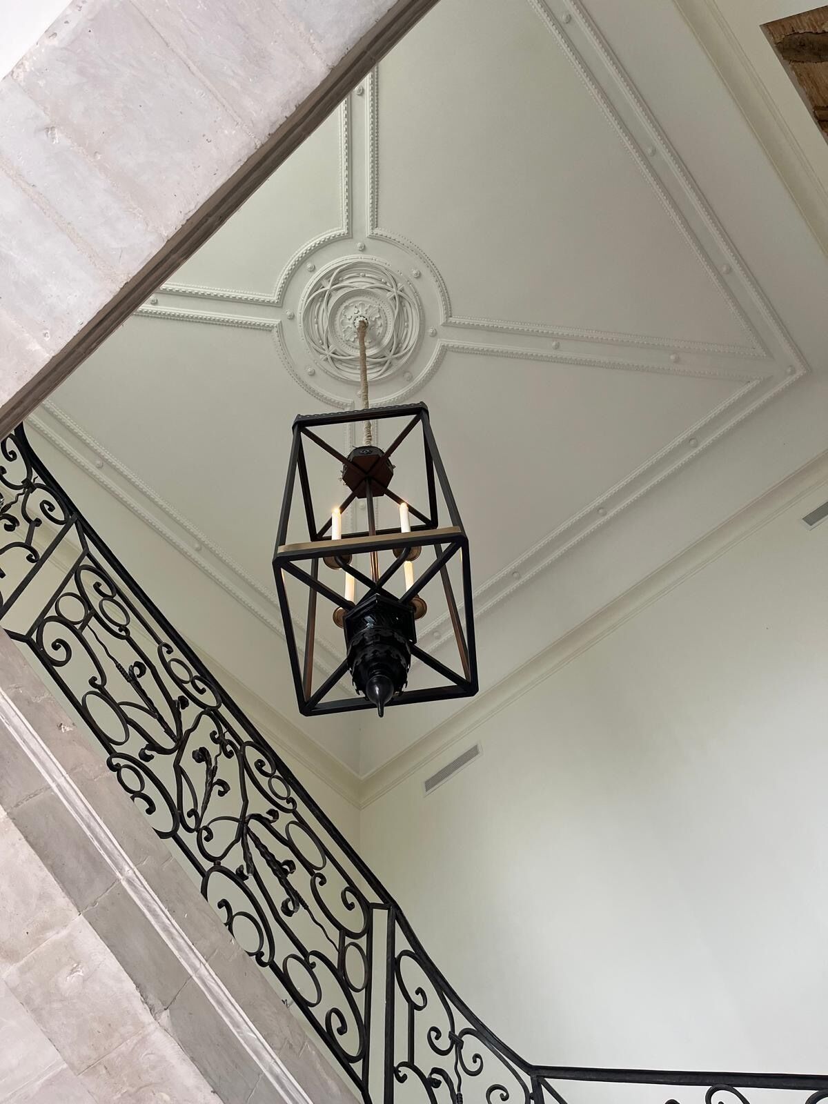 A staircase with a decorative railing and a hanging light fixture.