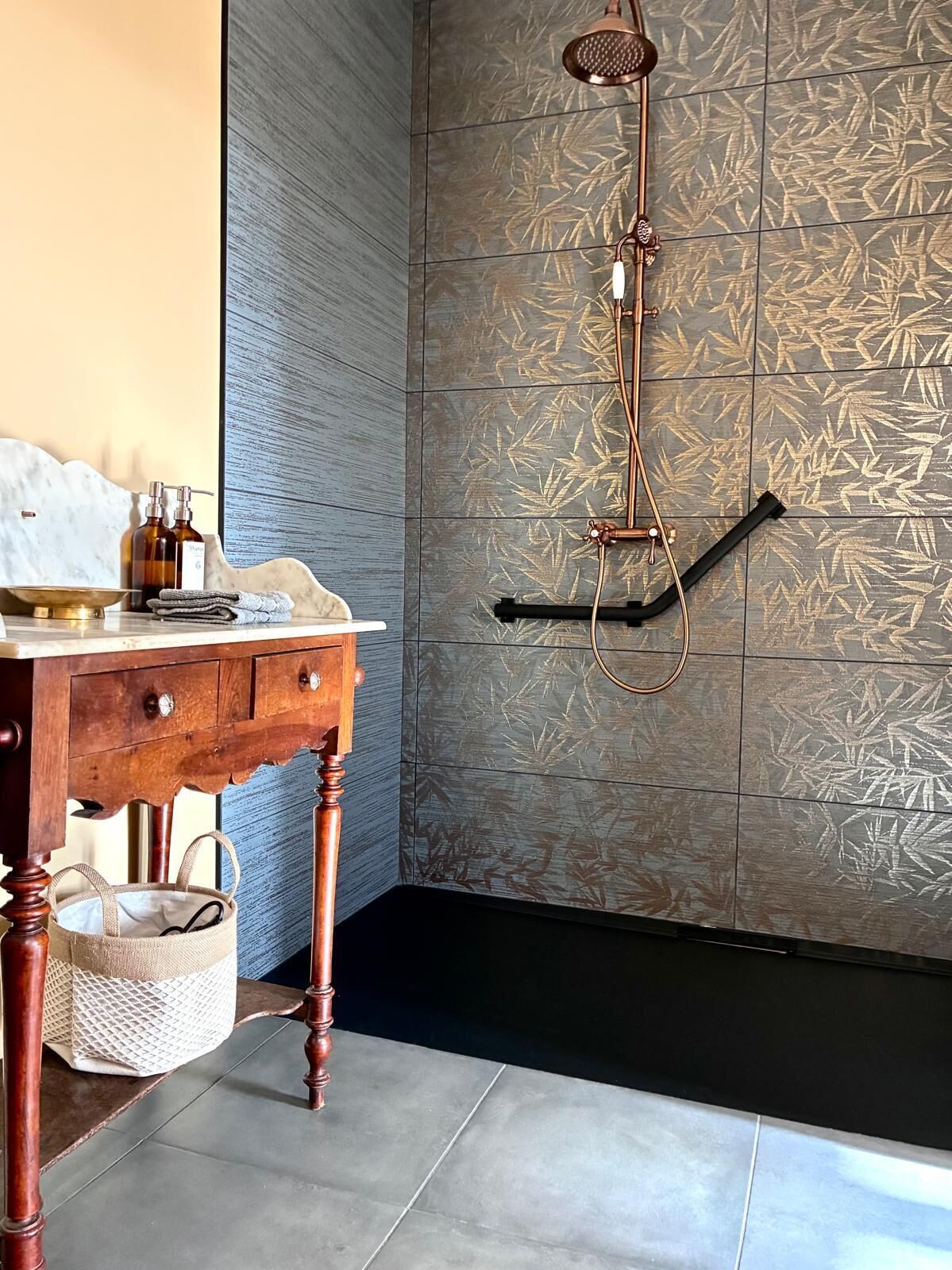 A bathroom with a wooden vanity, a shower with a bamboo leaf pattern, and a hanging towel rack.