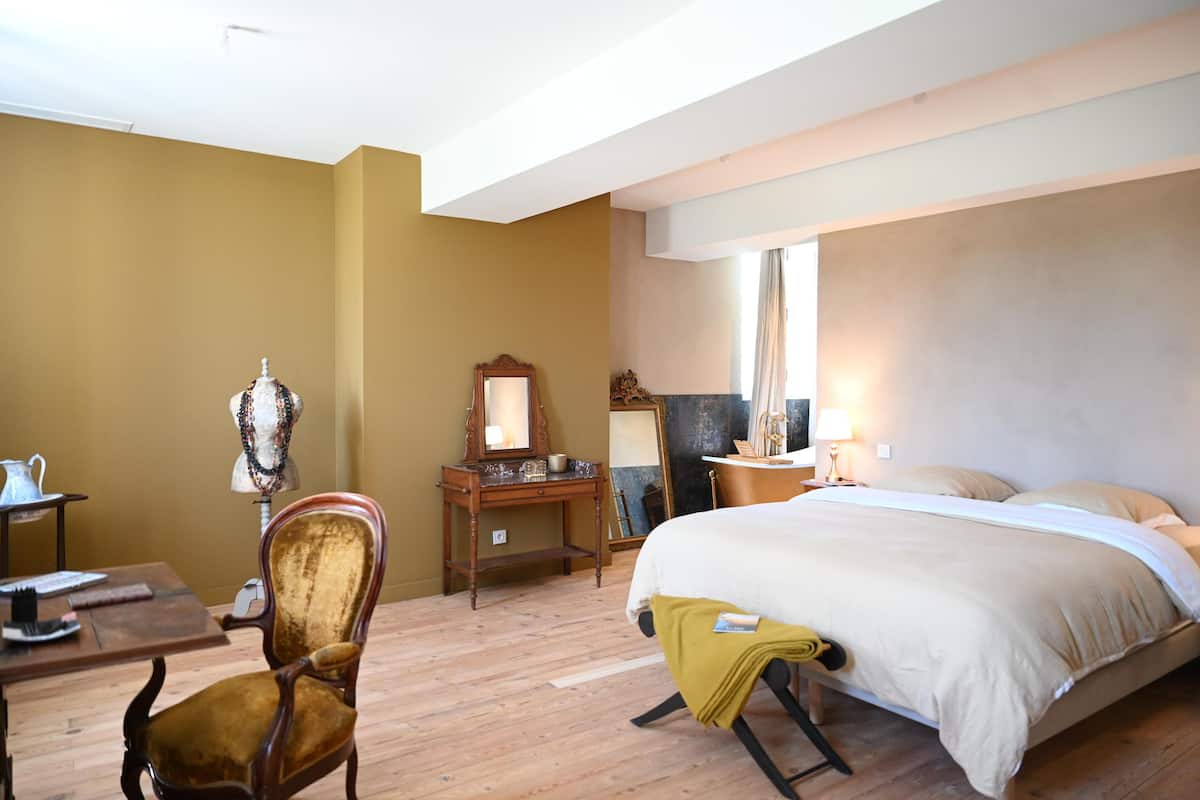 A hotel room with a bed, a desk, a chair, and a dresser.