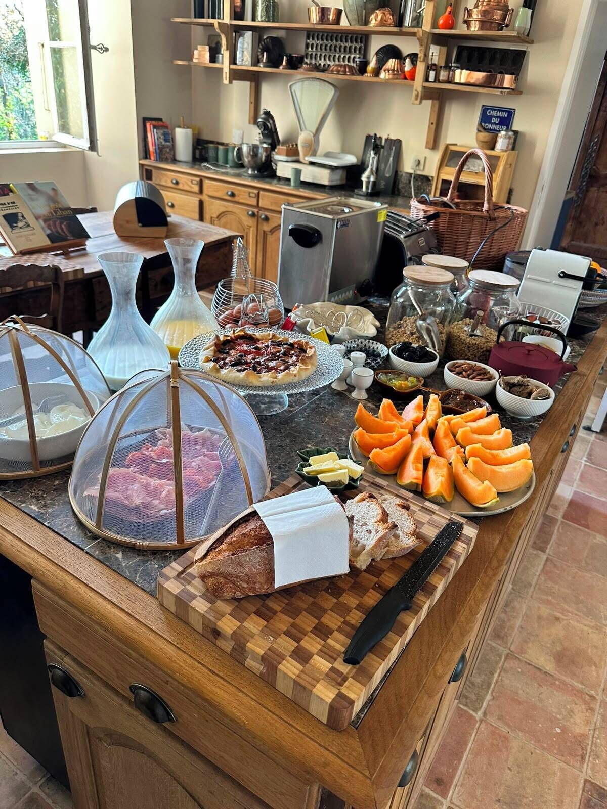 A kitchen counter with various food items, including a pizza, bread, and a variety of condiments.