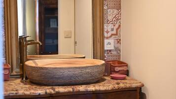 A bathroom vanity with a wooden basin, a large mirror, and a cabinet with drawers.