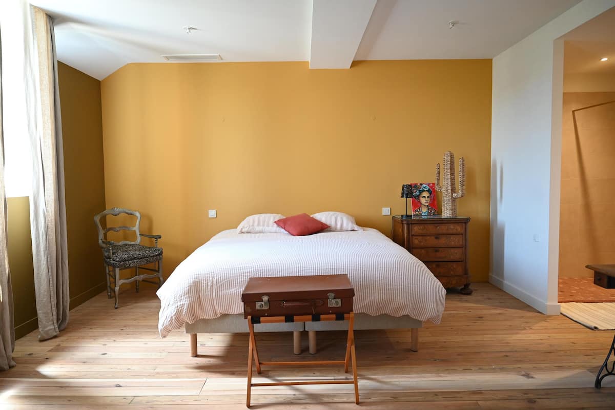 A bedroom with a bed, a wooden dresser, a chair, and a small table.