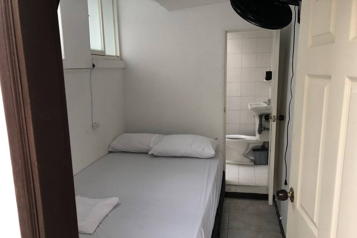 A small, clean room with a single bed, a window, a toilet, and a sink.