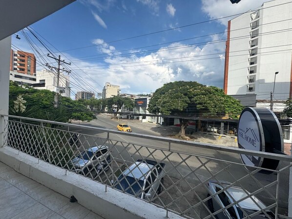 Ein Balkon mit Blick auf eine Straße, parkende Autos und ein Gebäude mit dem Schild 'ASL HOME'.