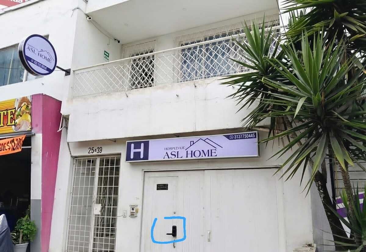 Um edifício com uma placa indicando 'ASL HOME' e uma entrada fechada por portão.