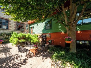 A courtyard with a wooden table and chairs, surrounded by potted plants and a tree. -  Downtown Easton Loft Cozy & Secluded - Walkable to shops, restaurants, & river (Easton)