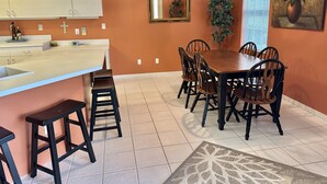 A dining area with a wooden table and chairs, a white countertop with a sink, and a decorative rug. - Resort-Style 3BR Home with Pool & Hot Tub in a Golf Course Community (Bonita Springs)