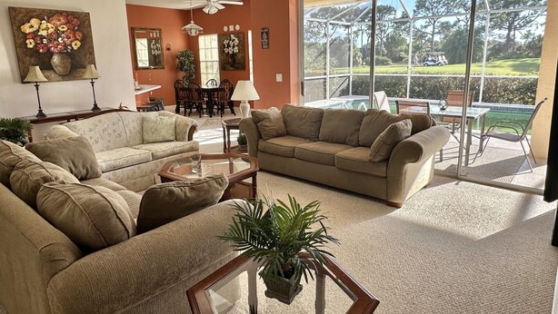 A spacious living room with two sofas, a coffee table, and a dining area with chairs and a table. - Resort-Style 3BR Home with Pool & Hot Tub in a Golf Course Community (Bonita Springs)