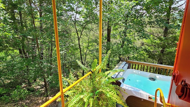 Tinaco en un área boscosa con una terraza de madera y barandas de seguridad amarillas.
