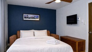 Ein Schlafzimmer mit einem Bett, einem Fernseher und einem Nachttisch aus Holz.