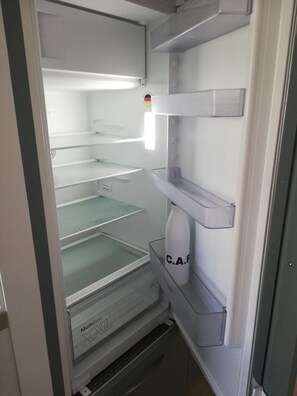 An empty refrigerator with multiple shelves and a water dispenser. - Charming apartment💕 Near beaches and shops. Secure parking (Loctudy)