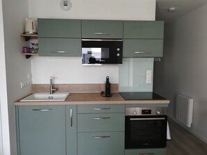 A modern kitchen with a sink, microwave, oven, and cabinets. - Charming apartment💕 Near beaches and shops. Secure parking (Loctudy)