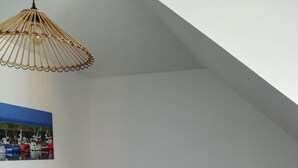 Un dormitorio con cama, lámpara colgante, mesita de noche y un cuadro en la pared.