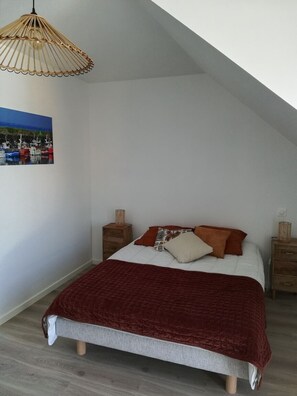 A bedroom with a bed, a hanging light fixture, a nightstand, and a wall-mounted picture. - Charming apartment💕 Near beaches and shops. Secure parking (Loctudy)