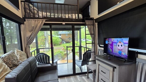 A modern interior with a loft bedroom, a sofa, a TV, and a dining area. - And.N Lodging  (Casco)
