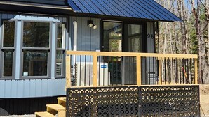 A cabin with a metal roof, large windows, and a wooden deck. - And.N Lodging  (Casco)