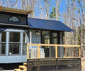 A cabin with a metal roof, large windows, and a wooden deck. - And.N Lodging  (Casco)