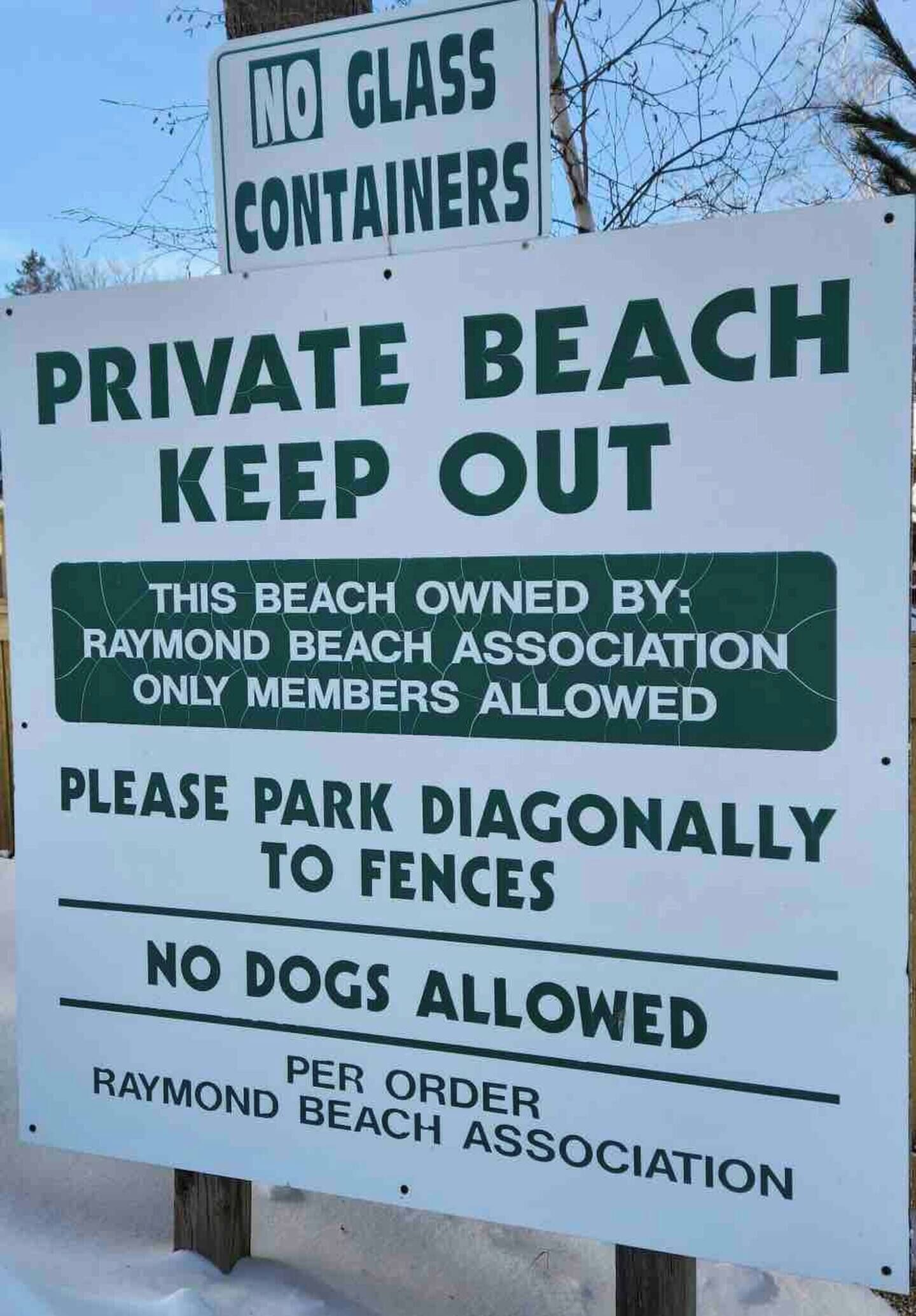 Schild, das einen privaten Strand mit Einschränkungen kennzeichnet: keine Glasbehälter, keine Hunde, und Parken diagonal zu den Zäunen.