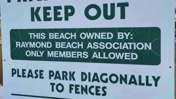 Señal que indica una playa privada con restricciones: prohibido el vidrio, no se admiten perros y estacionamiento en diagonal a las vallas.