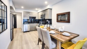 A modern kitchen with white cabinets, a microwave, and a herringbone-patterned backsplash. - Elegant 2BR Suite Close to Transit (Montréal)