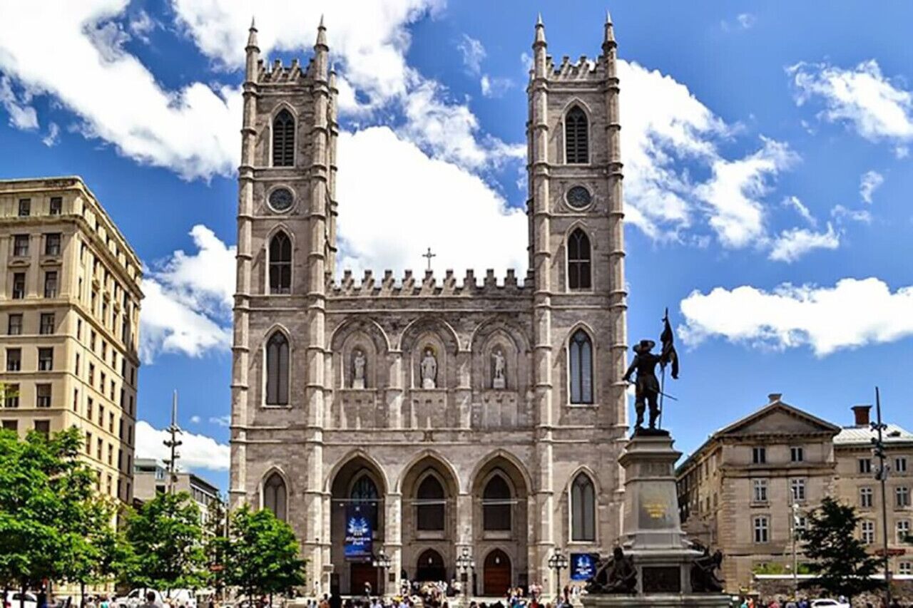 A historic cathedral with twin towers and a statue in front.