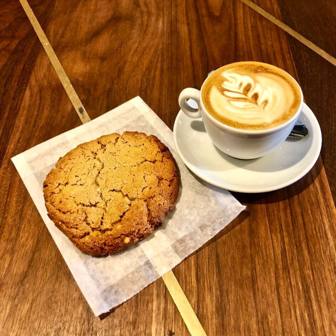 A cookie and a cup of coffee on a wooden table.