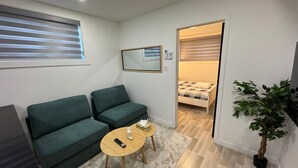 A compact living space with a green sofa, a small round table, and a potted plant. - NDG Treasure in Montreal! Value & Travel Adventure (Montréal)