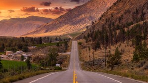 A straight road leading through a mountainous area with houses on the left and a forested hillside on the right. - $2,175 / 3br - 1450ft2 - 3 Beds 2 Baths House (Osoyoos) (Osoyoos)