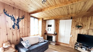 En mysig stuga med en soffa, en öppen spis, en tv och en björnstaty.