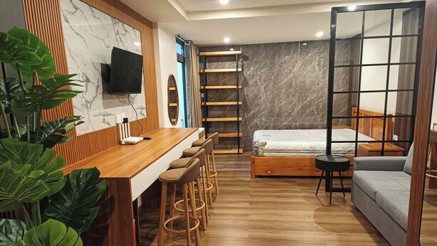 Un espace de vie moderne et compact, comprenant un bar en bois, un lit, un canapé et un téléviseur.