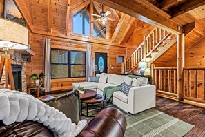 L’intérieur d’un chalet confortable, avec des murs en bois, un canapé blanc, un fauteuil en cuir et une cheminée.