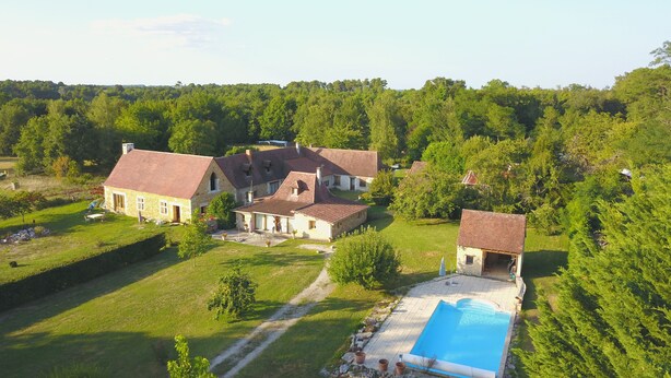 Ein weitläufiges Anwesen mit mehreren Gebäuden, einem Swimmingpool und üppiger Bepflanzung.