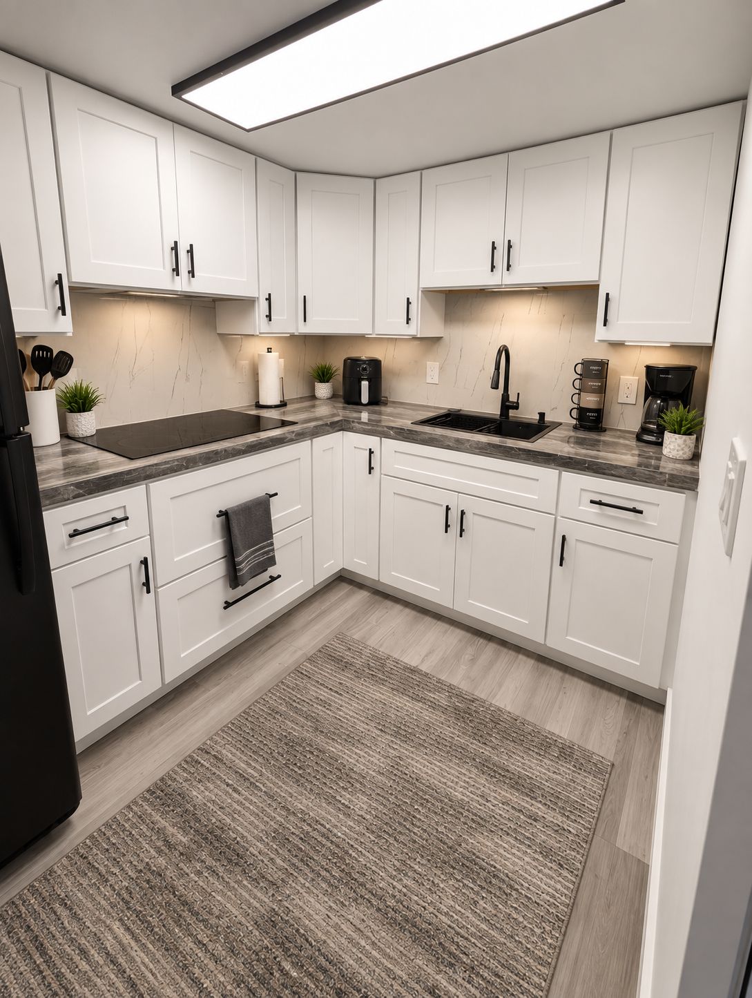 A modern kitchen with white cabinets, a black countertop, and a built-in stove.